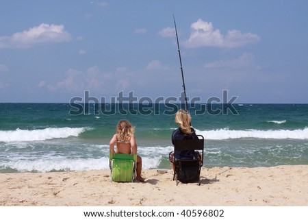 Two women fish on a sea beach