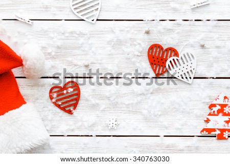 Snowflakes, Christmas cap and hearts on the wooden table with white snow. Christmas background, copy space. Top view.