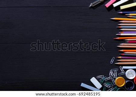 Back to school concept, colorful pencils on black art table, multicolored stationery supplies for teaching kids drawing on empty dark wooden desk, creative education background, top view, copy space
