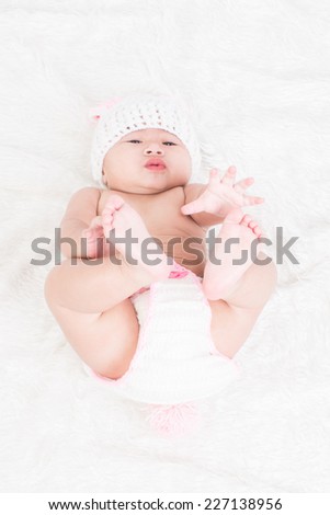 asian cute boy five month wearing a crochet hat on white carpet on white background