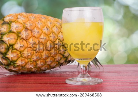 Fresh  pineapple and pineapple juice on wood table on green bokeh background