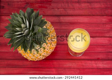 Fresh  pineapple and pineapple juice on red wood table