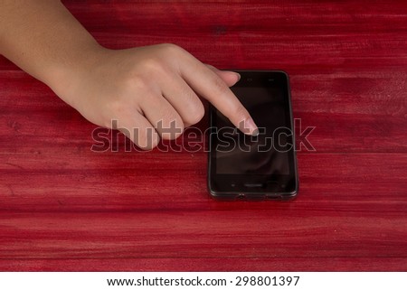Hand holding and touch on Black Smartphone with blank screen on wood table