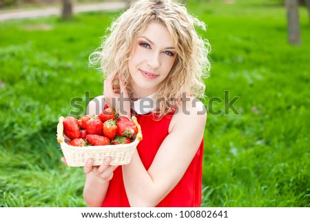 A beautiful young woman, a blonde with a basket of strawberries. Spring, bright green grass. A series of photos in my portfolio