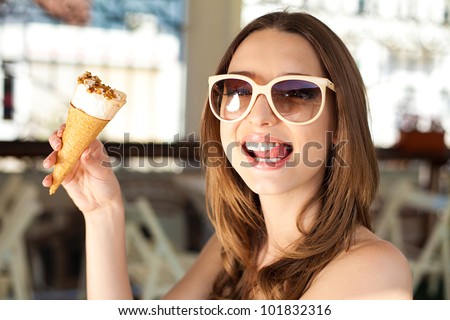 Beautiful young woman relaxing in a bar in the open air, with ice cream. A sunny day in summer.