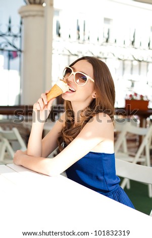 Beautiful young woman relaxing in a bar in the open air, with ice cream. A sunny day in summer.