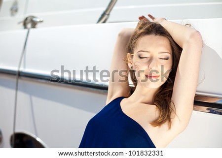 Young beautiful brunette woman relaxing on the dock near the boat on a sunny day in summer.