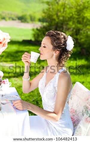 A beautiful bride poses on a green field in a park in the spring of your wedding day
