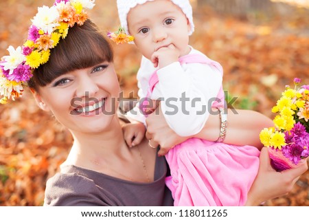 Family portrait cute little girl and cheerful mom. Posing in a park on a background of autumn leave. Series of photos in my portfolio