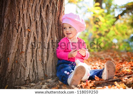 Portrait of a cute little baby posing in autumn park against fallen yellow leaves. Series of photos in my portfolio.