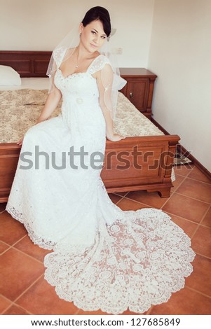 wedding Happy beautiful brunette bride in luxurious wedding dress sitting on bed waiting for groom