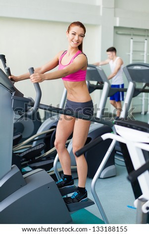 Attractive young fitness model exercising on a cardio machine inside in fitness center