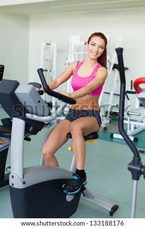 Attractive young fitness model exercising on a cardio machine inside in fitness center