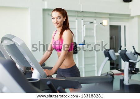 Attractive young fitness model runs on a treadmill, is engaged in fitness sport club
