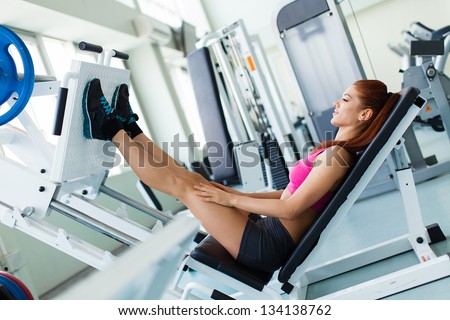 Attractive young fitness model works out on training apparatus inside in fitness center