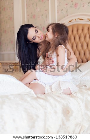 Portrait of mother and daughter in bed hugging and smiling. Morning