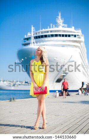 Beautiful Vacationing Woman in a dock, big cruise ship on background