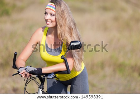 Attractive young model on bicycle standing on road. Cycle gear for cyclist trains for fitness.