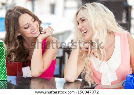 Two Beautiful Young Women Friends In Cafe On A Terrace After The Shopping