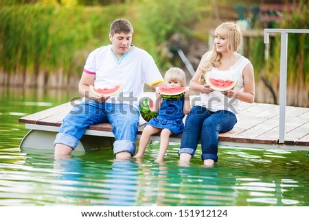 happy young family on picnic in the green park with lake