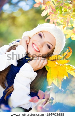 Excited happy fall woman smiling joyful and blissful holding autumn leaves outside in colorful fall forest