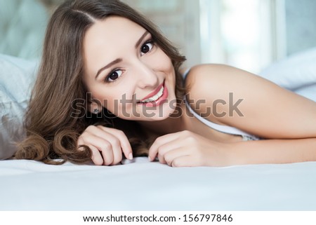 Portrait of young woman lying at the bed at early morning