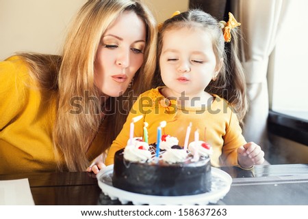 Mom and young daughter celebrating a birthday with cake