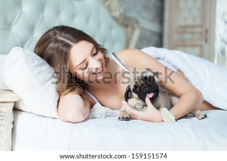 Attractive young girl with dog while laying on a bed Attractive young girl with dog while laying on a bed