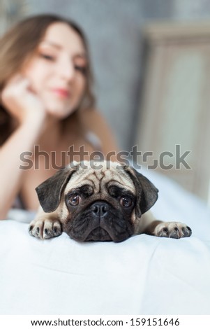 Attractive young girl with dog while laying on bed, focus on a dog