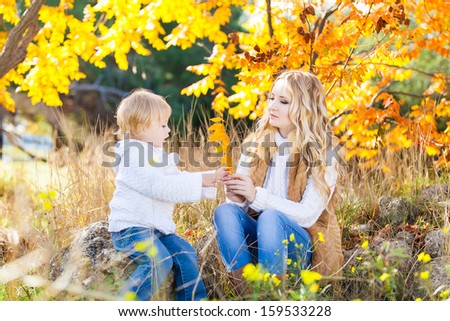 Young mother playing with her daughter in autumn park