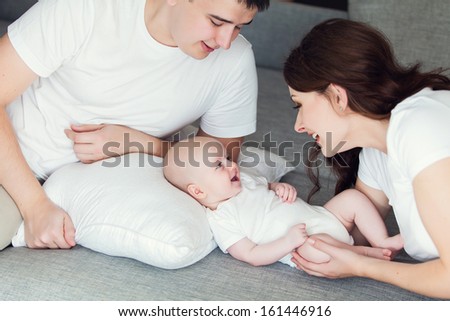 mother and father playing with their cute baby on the couch at home
