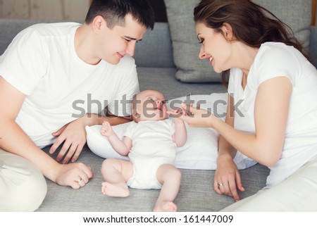 mother and father playing with their cute baby on the couch at home