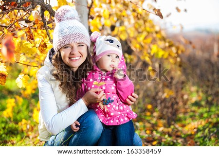Young mother and her cute girl have fun in autumn vineyard