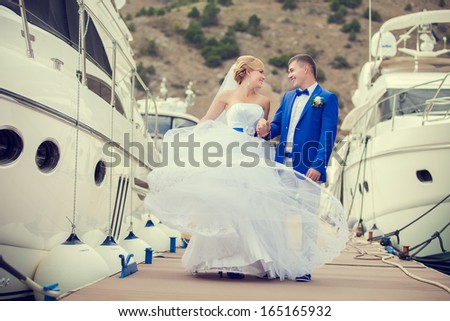 Couple in love the bride and groom look at each other on pier with yachts