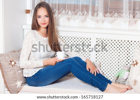 Happy young woman sitting, holding coffee mug, laughing