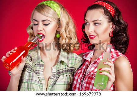 Beautiful pinup girls drinking soft drink from glass bottle