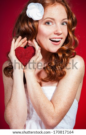 Portrait of a beautiful young woman holding Love symbol red heart. against a red background