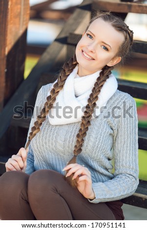 Portrait of lovely young female sitting on steps and smiling