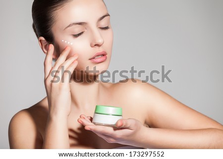 A young woman applying anti-wrinkle cream