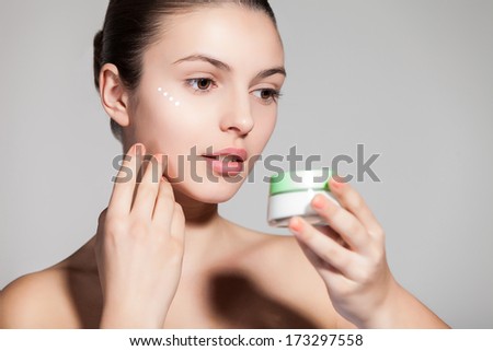 A young woman applying anti-wrinkle cream