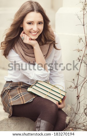 Portrait of young happy smiling cheerful college student in park with a books