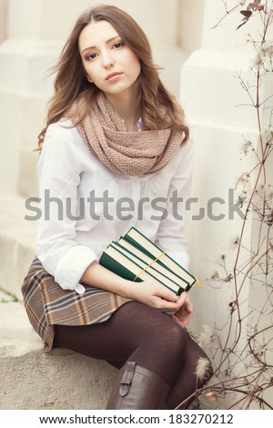 Portrait of young happy smiling cheerful college student in park with a books