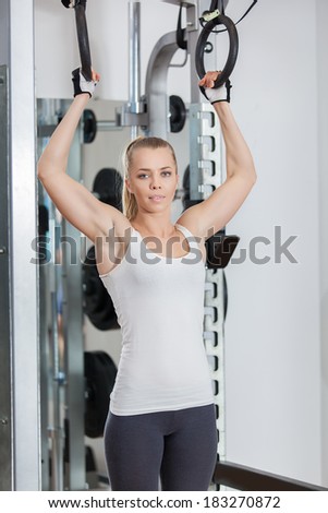 Attractive young fitness model works out on training apparatus in fitness center