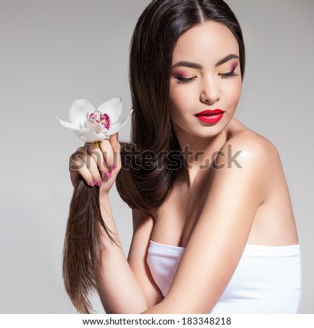 Beauty Portrait. Beautiful Stylish Girl with Orchid Flower. Perfect Face Skin. Healthy hair