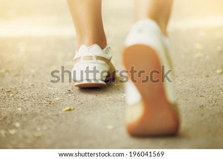 Runner feet running on road closeup on shoe.  Female jogging in Park