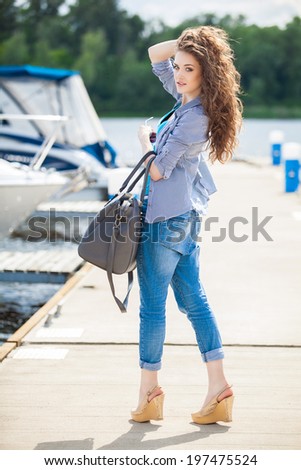 Young beautiful woman relaxing on the dock near the boat on a sunny day