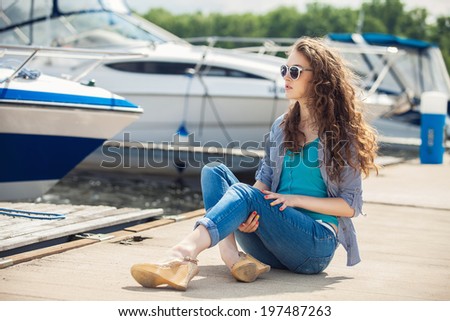 Young beautiful woman relaxing on the dock near the boat on a sunny day