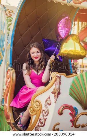 Beautiful young girl riding on a merry go round
