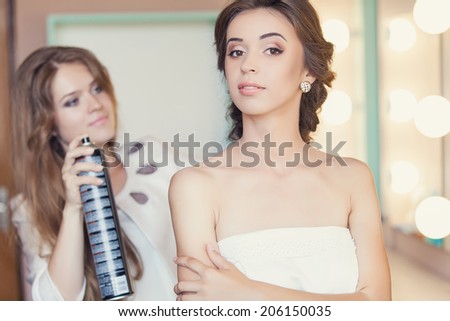 Beautiful bride applying wedding make-up by professional make-up artist on the wedding day