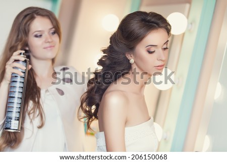 Beautiful bride applying wedding make-up by professional make-up artist on the wedding day